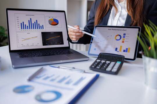 Business woman accountant analyzing data charts, graphs, and a dashboard on a laptop screen in order to prepare a statistical report and discuss financial data in an office
