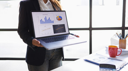 Woman finance business of a business professional analyzing a spreadsheet dashboard on a laptop while taking notes.