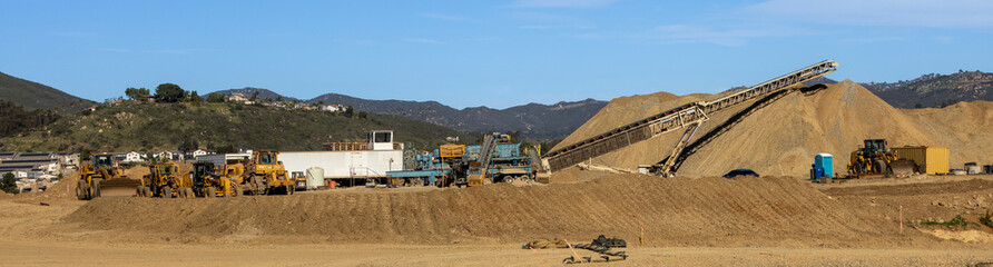 A conveyor machine and a large mound of dirt and gravel at a construction site