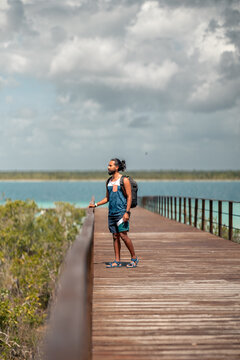 Hombre joven latino viajero, parado en un muelle de madera, contemplando la laguna de Bacalar, Quintana Roo, M&eacute;xico, hombre disfrutando la vista desde el muelle