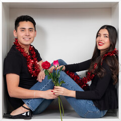 Young couple in a box with roses and red tinsel for Valentine's Day celebration