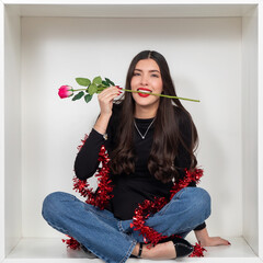 Young woman with a pink rose in her mouth and red tinsel around her neck