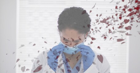 Adjusting clinician in lab coat, scrub top pulling blue mask at window blinds, blue gloves, hearts