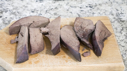 Cooking pork liver on a wooden cutting board in a kitchen