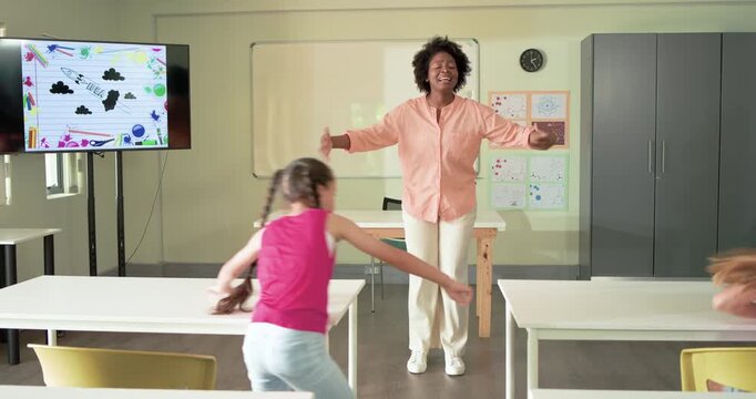 Female teacher with kids gesturing front, inviting hug; girl running, kids hugging her near clock