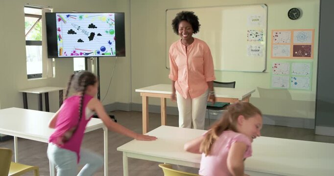African American woman teacher in peach blouse gesturing inviting youth running and hugging desks