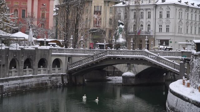 Ljubljanica river flowing through the snow covered old town Ljubljana, Slovenija. Zoom in.