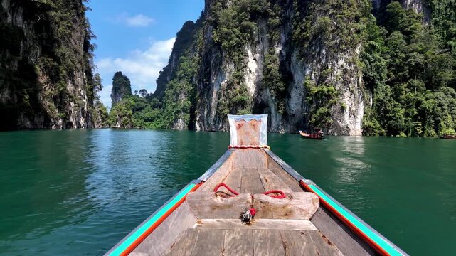 Experience the beauty of Khao Sok, Thailand, where traditional longtail boats glide through emerald waters surrounded by towering cliffs and lush jungles. Natures paradise awaits.
