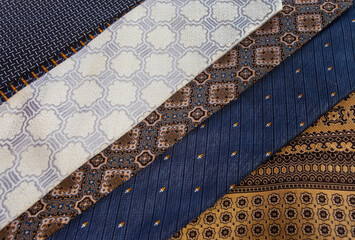 Full frame texture of colorful tie fabrics. Assortment of silk neckties with diverse motifs like stripes and batik, perfect for menswear fashion concepts