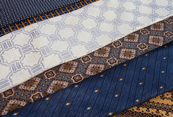 Full frame texture of colorful tie fabrics. Assortment of silk neckties with diverse motifs like stripes and batik, perfect for menswear fashion concepts