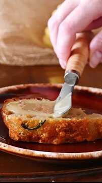 Spreading creamed honey on slice of sourdough bread and taking a bite