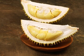 Fresh durian fruit slice served on wooden plate. Exotic tropical fruit with creamy texture and...