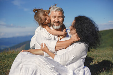 Fototapeta premium Grandparents in summer mountains with granddaughter