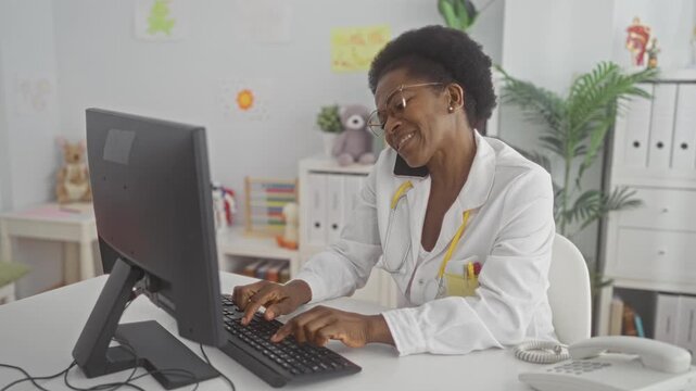 Woman doctor typing on keyboard with phone wedged between shoulder and ear in pediatric clinic building; compassion telemedicine.
