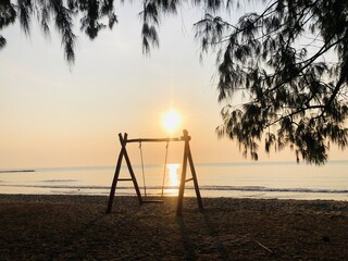 Naklejka premium swing on the beach,a couple watching the sunset on the beach on a swing,white tropical beach during sunset,swing on the beach during sunset,Empty hammock swing on the beautiful beach and sea