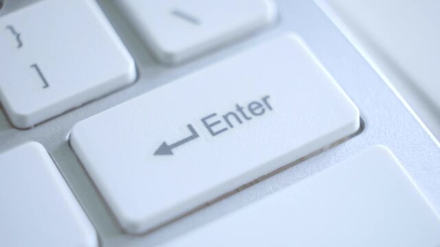 Close-up view of a person's finger pressing the enter key on a computer keyboard for digital interaction