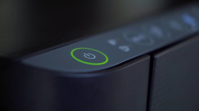 Macro shot of finger pressing power button on a printer device control panel