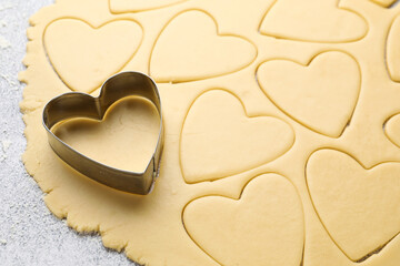 Obraz premium Heart shaped cookie cutter and raw dough on table, closeup