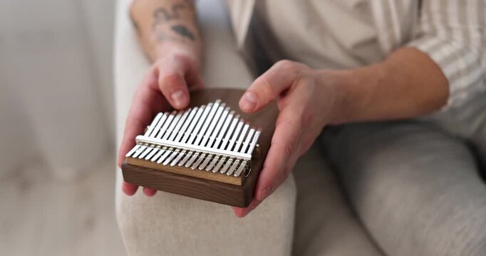 Man playing kalimba on sofa at home, closeup