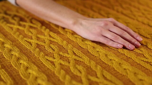 Woman touching soft yellow knitted fabric, closeup