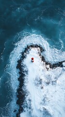 Snowy lighthouse vista: Coastal structure amidst winter's turbulent embrace