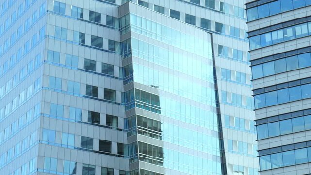 Smooth slow panning closeup of modern generic glass skyscrapers facade with blue reflective window panels, corporate office building architecture background, commercial high rise exterior, no people