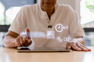 Senior man using tablet with virtual customer service icons, AI chat support and 24/7 service concept. Modern technology, digital communication, online help and smart assistance at home.