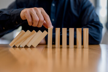 risk management and business protection concept. Preventing failure, stability control, crisis prevention, strategic planning and leadership decision making,Hand stopping falling wooden blocks
