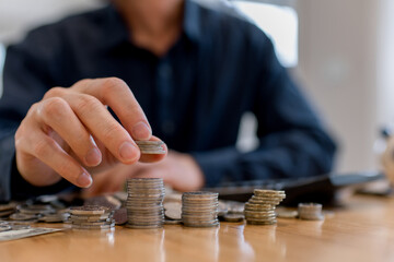 Man stacking coins on table, saving money and financial growth concept. Personal finance, investment planning, wealth accumulation, budgeting strategy and long-term economic stability.