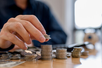Man stacking coins on table, saving money and financial growth concept. Personal finance, investment planning, wealth accumulation, budgeting strategy and long-term economic stability.