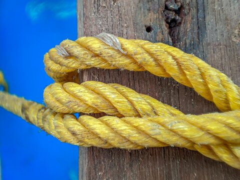 Yellow Twisted Rope Wrapped Around Weathered Wooden Post