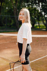 Woman with raquet and box of balls walk on court