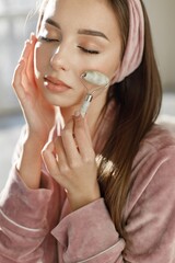 Portrait of brunette woman using a face roller