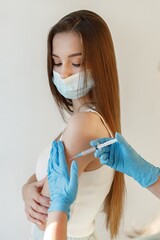 Woman in mask receiving an injection in her arm