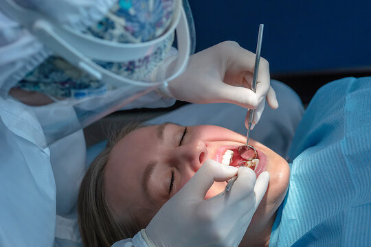 Dentist examining patient teeth during routine dental checkup. Close-up of professional oral examination with dental mirror and probe in a modern clinic, preventive care and oral health concept.