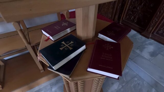Several books are placed on an altar in a church. The wooden furniture surrounds the area. The atmosphere shows a space for reading and reflection during services.