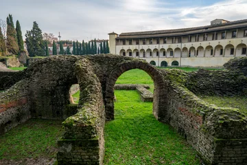 Roman Amphitheater ruins with arches and stone walls covered in moss in Arezzo, Italy © Luis