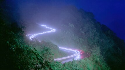 Winding mountain road with car light trails through a mystical misty forest, creating an adventurous journey over dark moody landscape