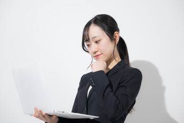 パソコンを持つスーツの若い女性　新卒や就職のビジネスイメージ　就活の採用イメージ考える　白背景(白バック)