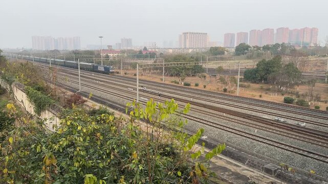 CHENGDU, CHINA - JANUARY 19, 2026: 4K 60fps video with sound showing a China Railway HXD electric locomotive (Harmony series) pulling a conventional green passenger train. The train passes by a reside