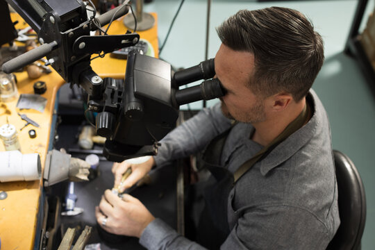 A jeweller looking through a scope while working on a piece of jewellery