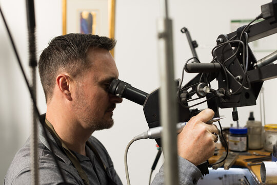 A jeweller looking through a scope while working on a piece of jewellery