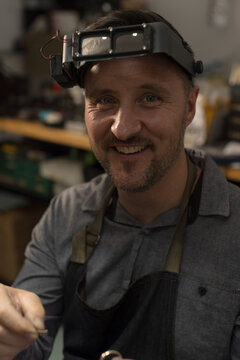 Portrait of a jeweller holding a ring in workshop