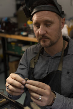 A jeweller looking at a ring he is holding a ring in his hands