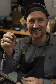 Portrait of a jeweller holding a ring in workshop