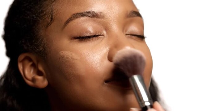 Close up of a woman's face as makeup is applied with a brush