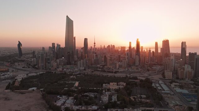 Drone aerial of Kuwait City at sunset, Al Hamra Tower and modern skyscrapers glowing over coastal highway and Arabian Gulf waterfront, cinematic golden hour cityscape.