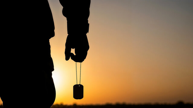 Soldier&rsquo;s hand holding dog tag at sunset symbolizing remembrance and identity