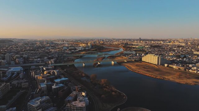夕暮れの多摩川上空、登戸と和泉多摩川を結ぶ鉄橋（ドローン空撮）