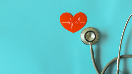 close up on red heart shape with pulse and stethoscope on blue background for insurance health...